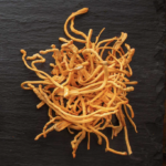 Dried orange cordyceps mushrooms on a dark slate surface